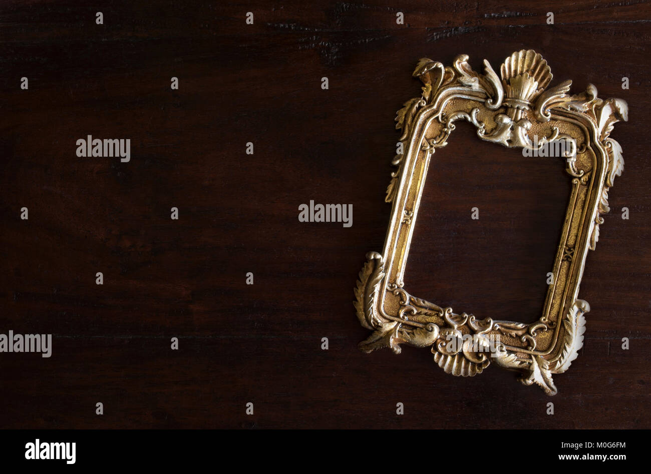 antiq golden photo frame in Rococo style, on dark rustic wooden background Stock Photo