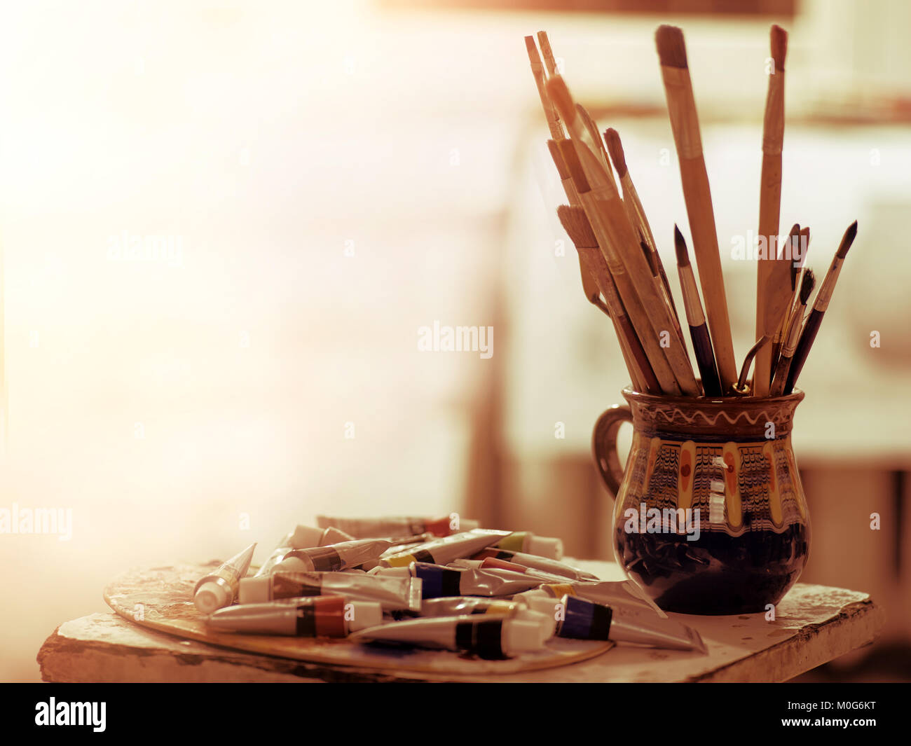 Paint brushes art pot. Easel with oil and watercolor paints Stock Photo