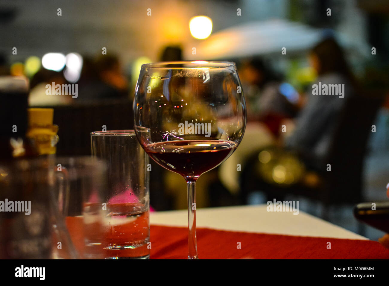A half empty glass of wine sits on the table of a sidewalk cafe in Split Croatia Stock Photo