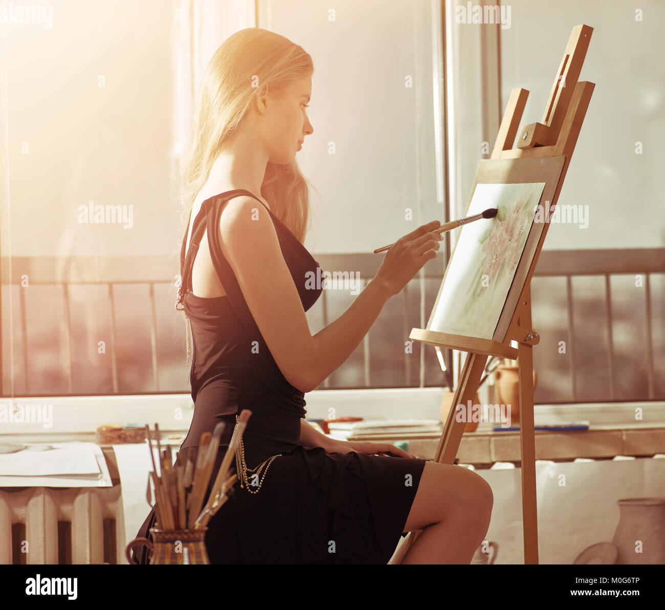 Artist painting on easel in studio. Girl paints with brush Stock Photo ...