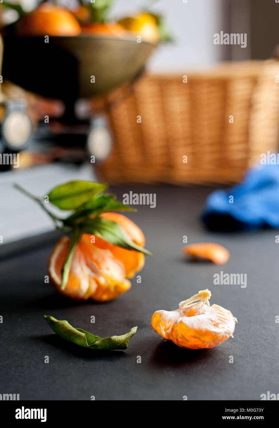 A bunch of fresh juicy clementines with green leaves in a scalepan and on a black table Stock Photo
