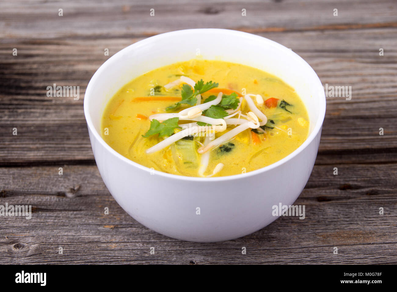 delicious thai curry coconut chiken soup bowl over rustic plank background Stock Photo
