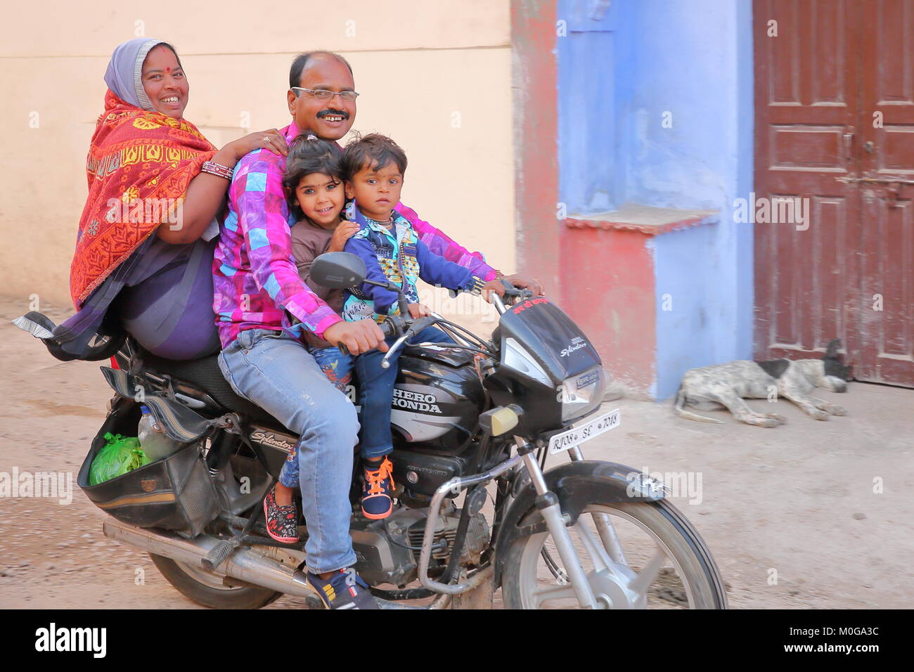 BUNDI, RAJASTHAN, INDIA - DECEMBER 10, 2017: Local transport with a smiling family travelling on a motorcycle in the streets of the old town Stock Photo