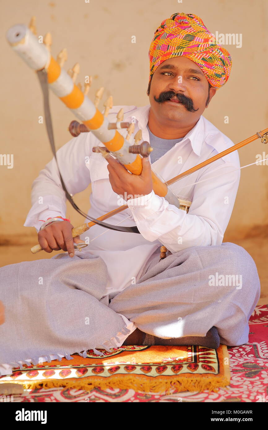 JODHPUR, RAJASTHAN, INDIA - DECEMBER 17, 2017: Portrait of a musician (with a nice mustache and colorful turban) playing a traditional instrument Stock Photo