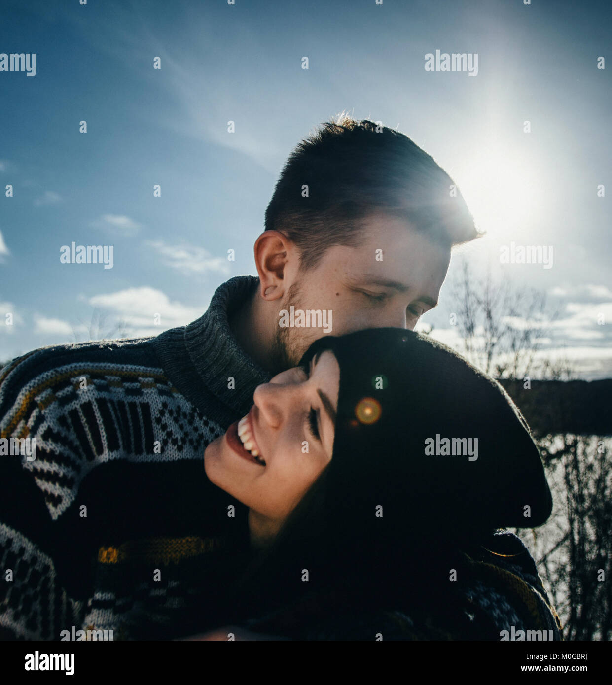 Joyful cute couple embraces. Young man in a sweater hugs a girl and kisses her in winter. The concept of a successful relationship and happy moments Stock Photo