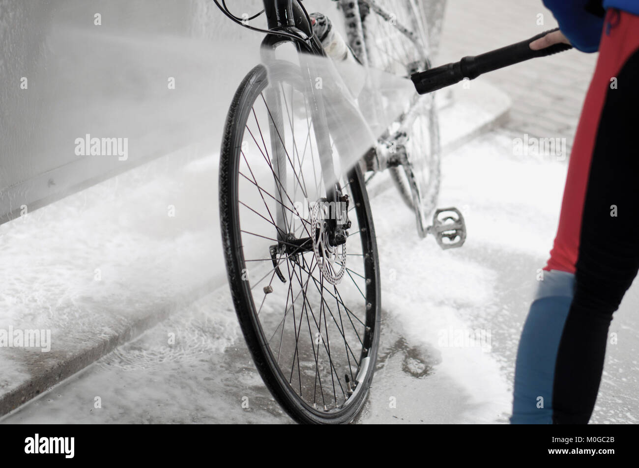 man washing the bike with a strong jet of water, washing the bike after