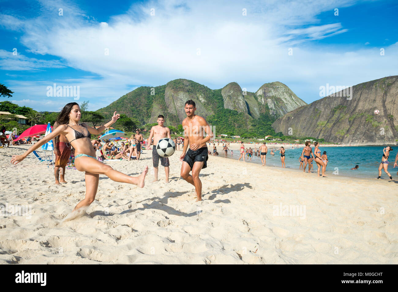 RIO DE JANEIRO - MARCH 20, 2017: Young Brazilians play a game of keepy-uppies (known locally as altinho) on the shore of Itacoatiara Beach. Stock Photo
