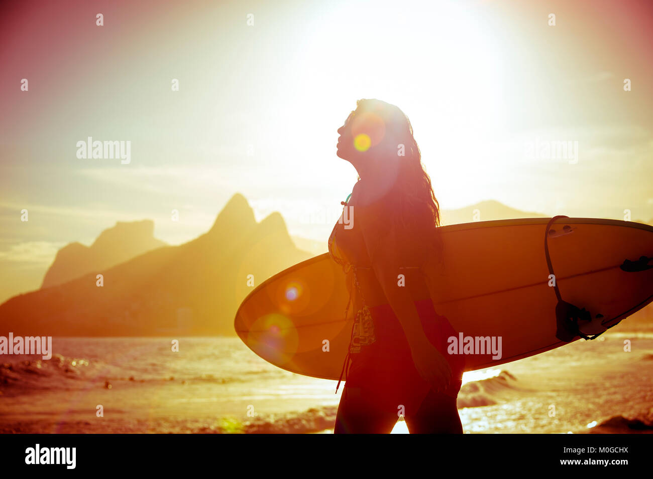 Unrecognizable silhouette of female surfer walking with her surfboard at Arpoador, the popular surf break in Rio de Janeiro, Brazil Stock Photo