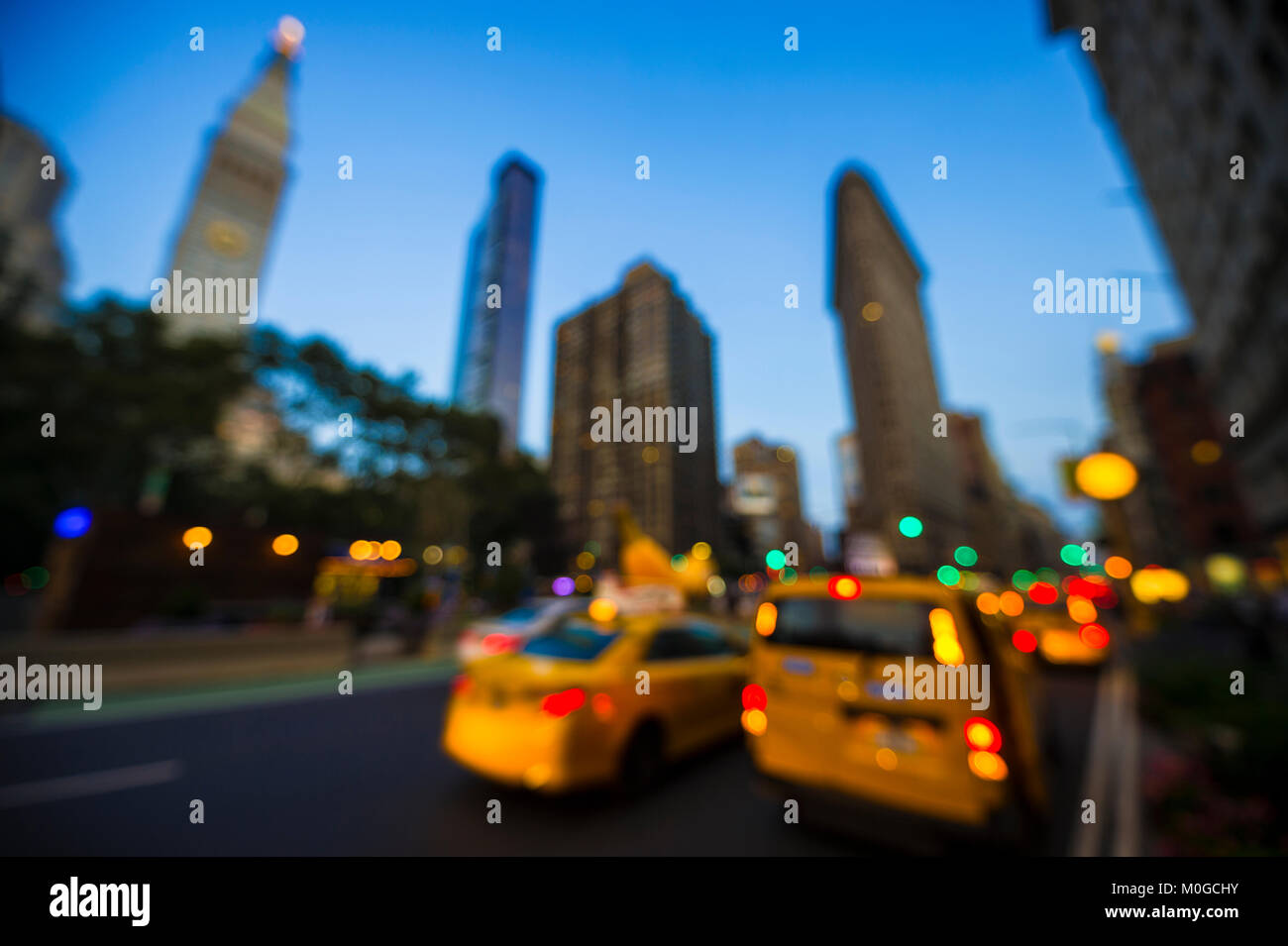 Abstract defocus view of yellow taxis driving through the city streets at dusk in New York City, USA Stock Photo