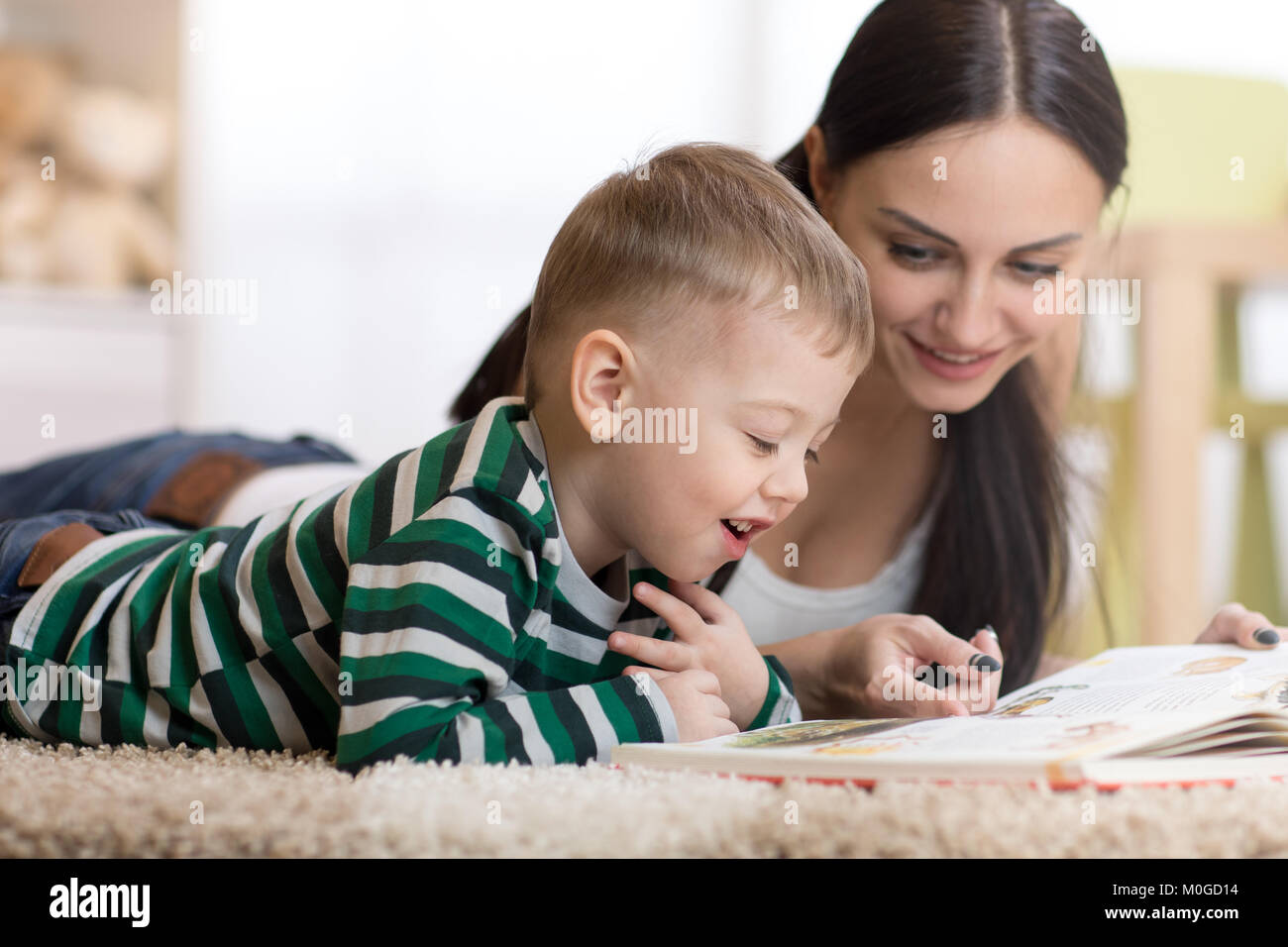 young mom and her child son lie on the floor and reading book Stock