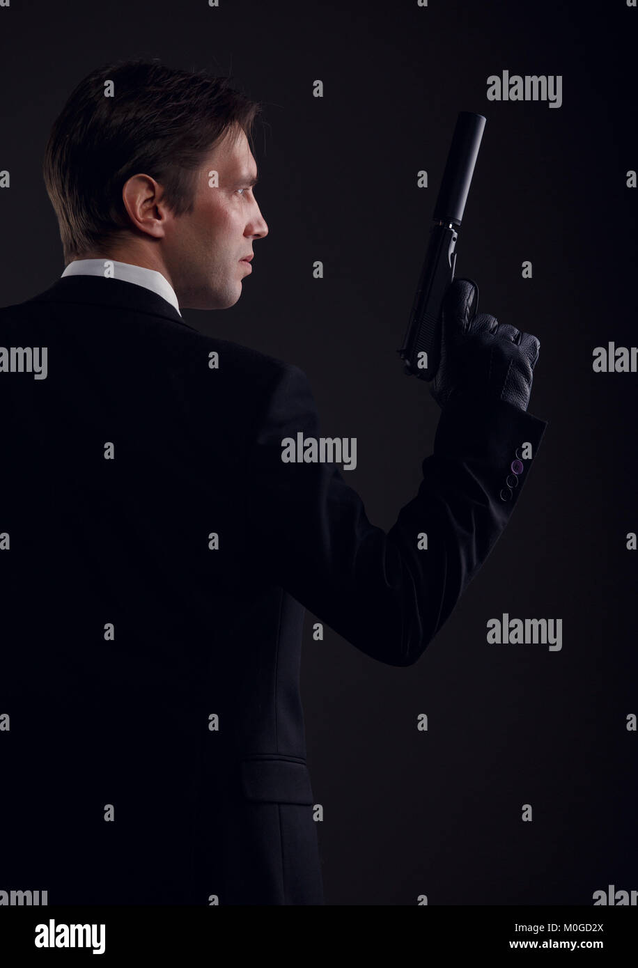 Photo from back of gangster man in leather gloves with gun Stock Photo