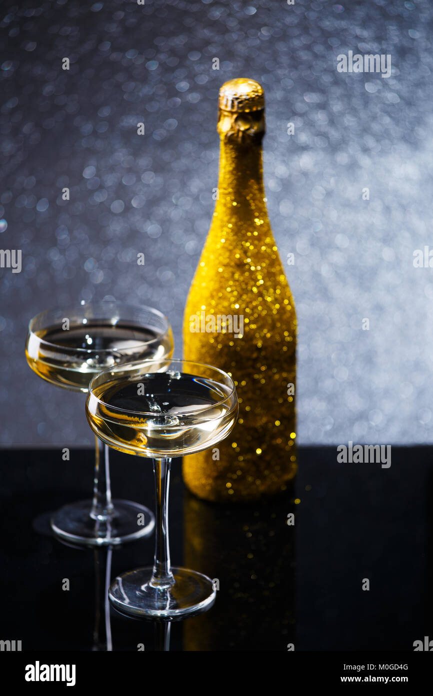 Festive image of bottle of champagne in gold wrapper with two wine glasses Stock Photo
