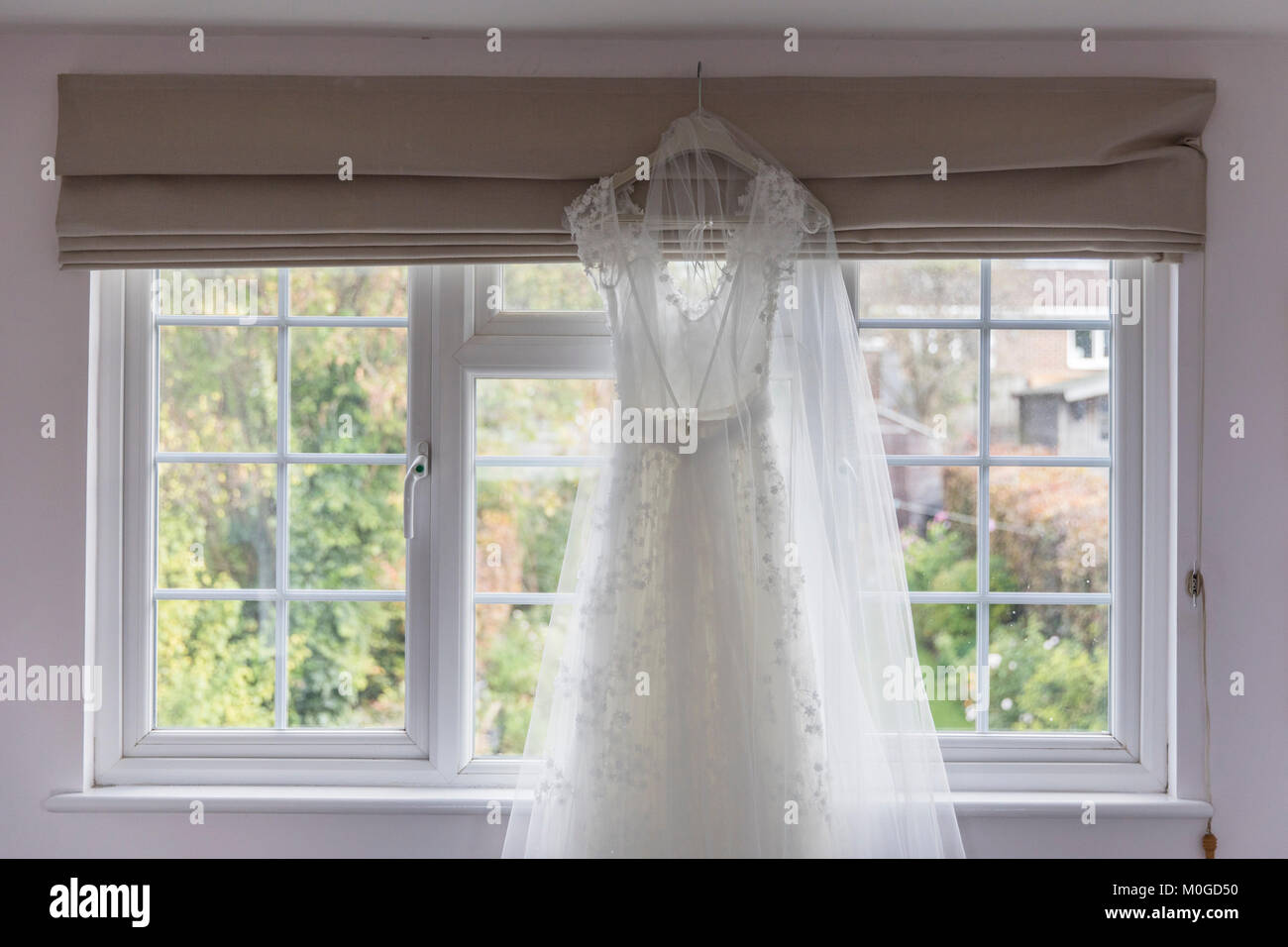 Wedding dress hanging in a window Stock Photo - Alamy