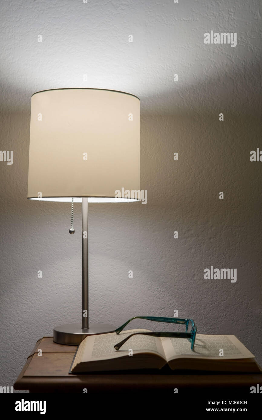 A pair of broken reader glasses resting on an old open book, underneath