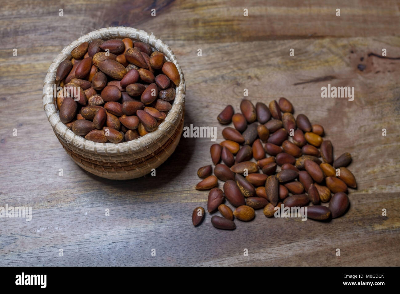 A small basket with pine nuts deorated with pine nuts on aged wooden table Stock Photo