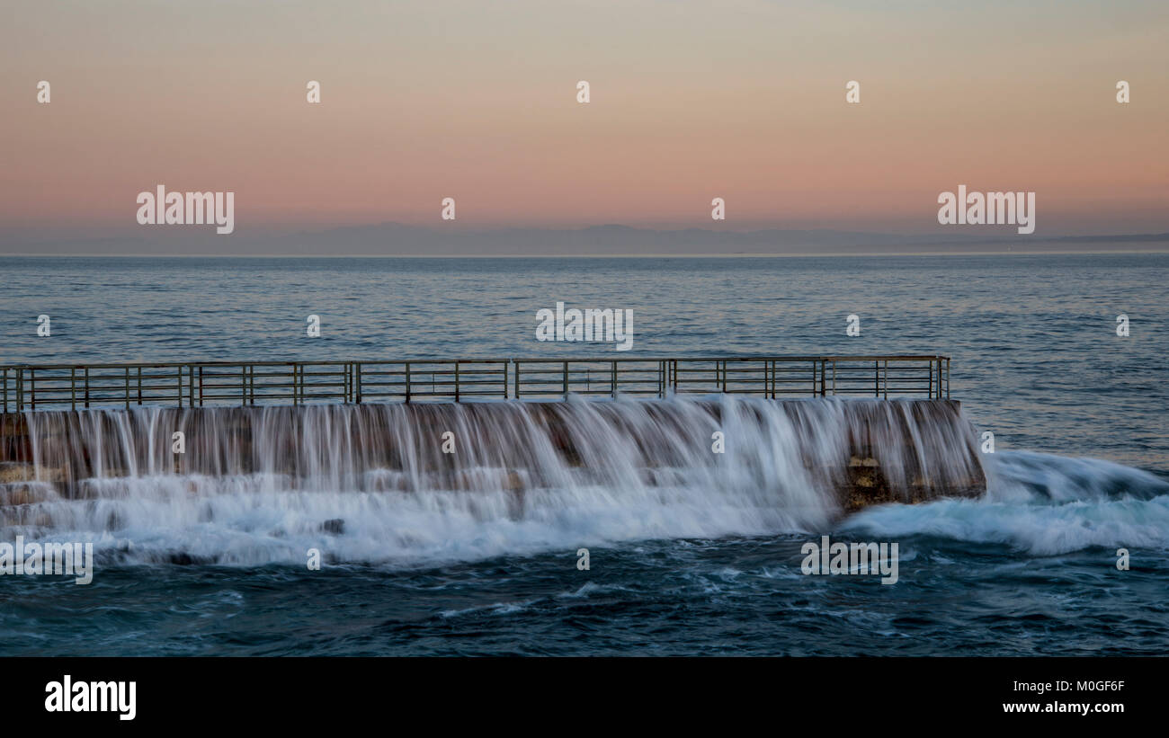 Breakwall at Children's Pool in La Jolla California in a long exposure as waves wash over and around it in the early morning. Stock Photo