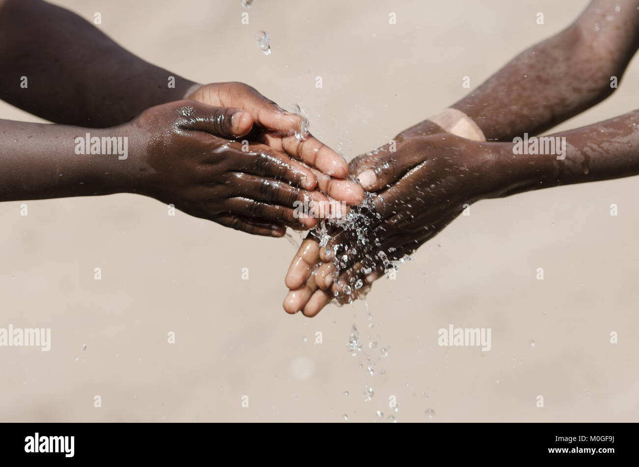 African Children Washing their Hands with Water Outdoors Stock Photo