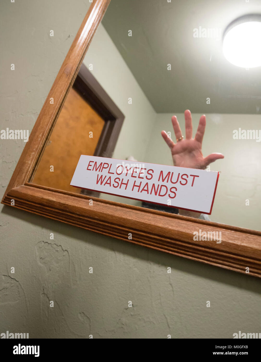 Employees must wash their hands sign on a restaurant bathroom mirror. Stock Photo