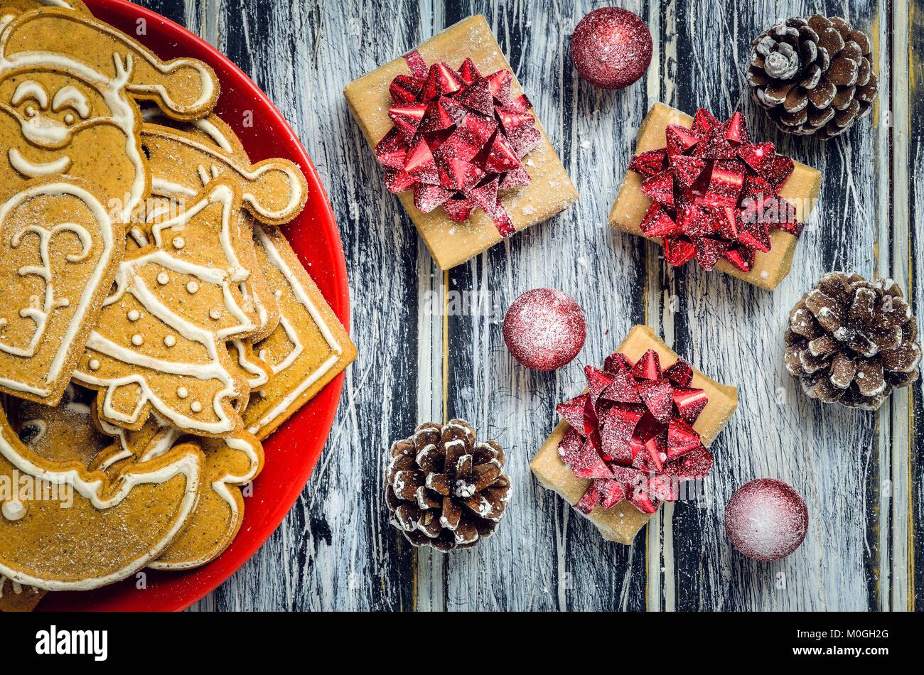 Christmas concept with gingerbread, gifts and snow. Sweet gingerbreads, gifts and baubles on a wooden table. Stock Photo