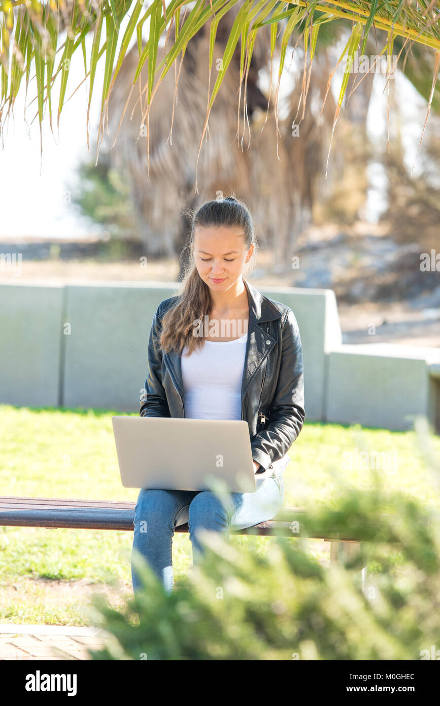 Beautiful young woman working on laptop in the park Stock Photo - Alamy