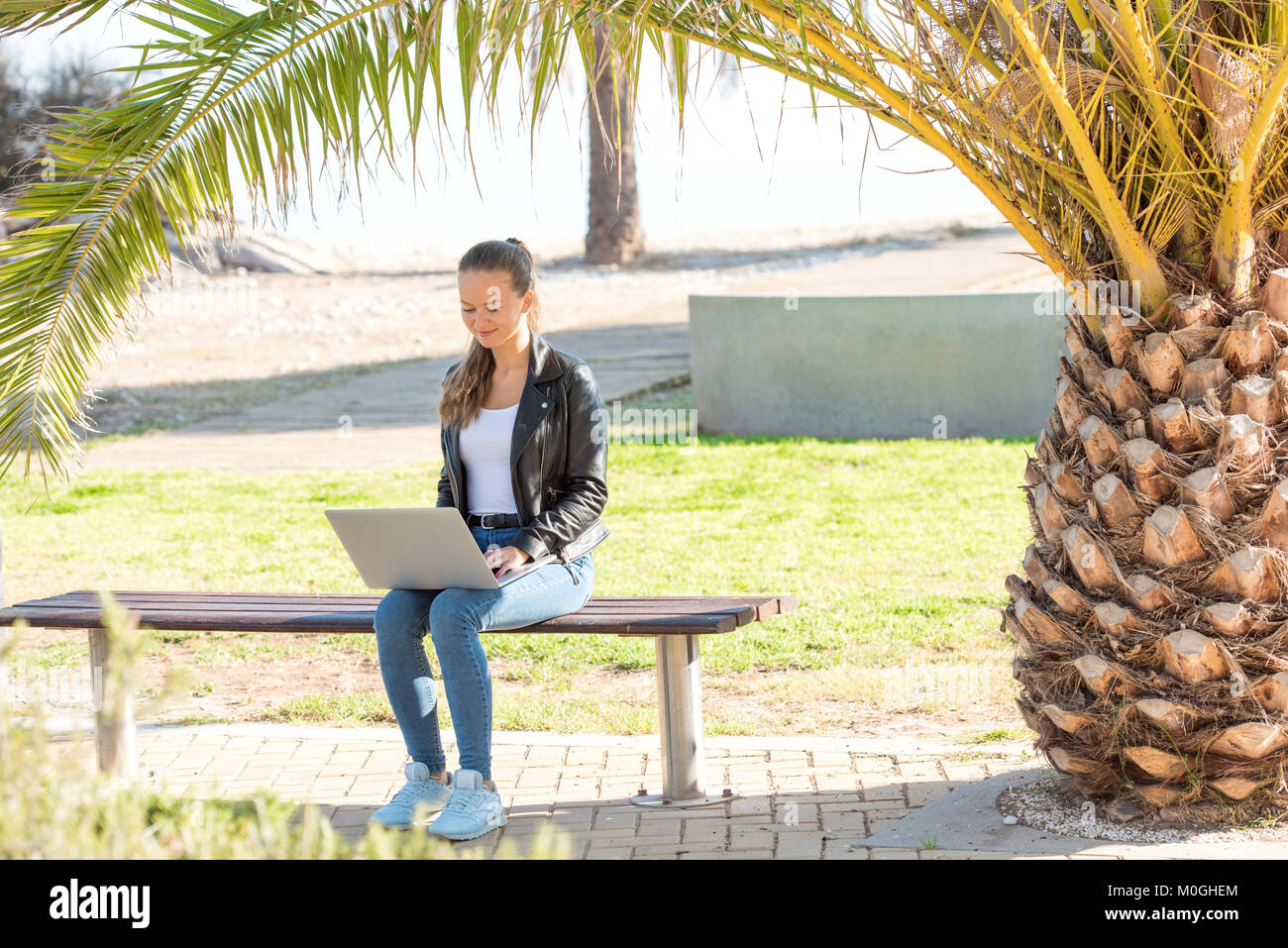 Beautiful young woman working on laptop in the park Stock Photo - Alamy