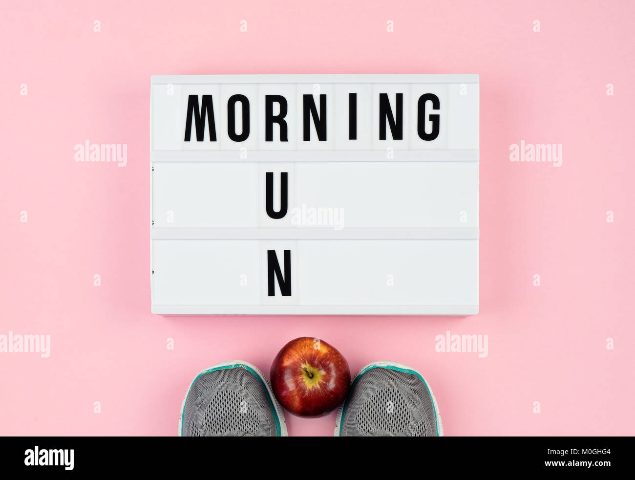 Motivation quotes on light box, apple and sport shoes on the pink Stock Photo