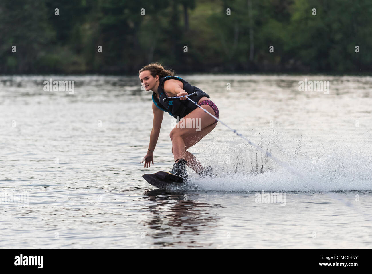 A teenage girl wakeboarding behind a boat on a lake; Lake of the Woods