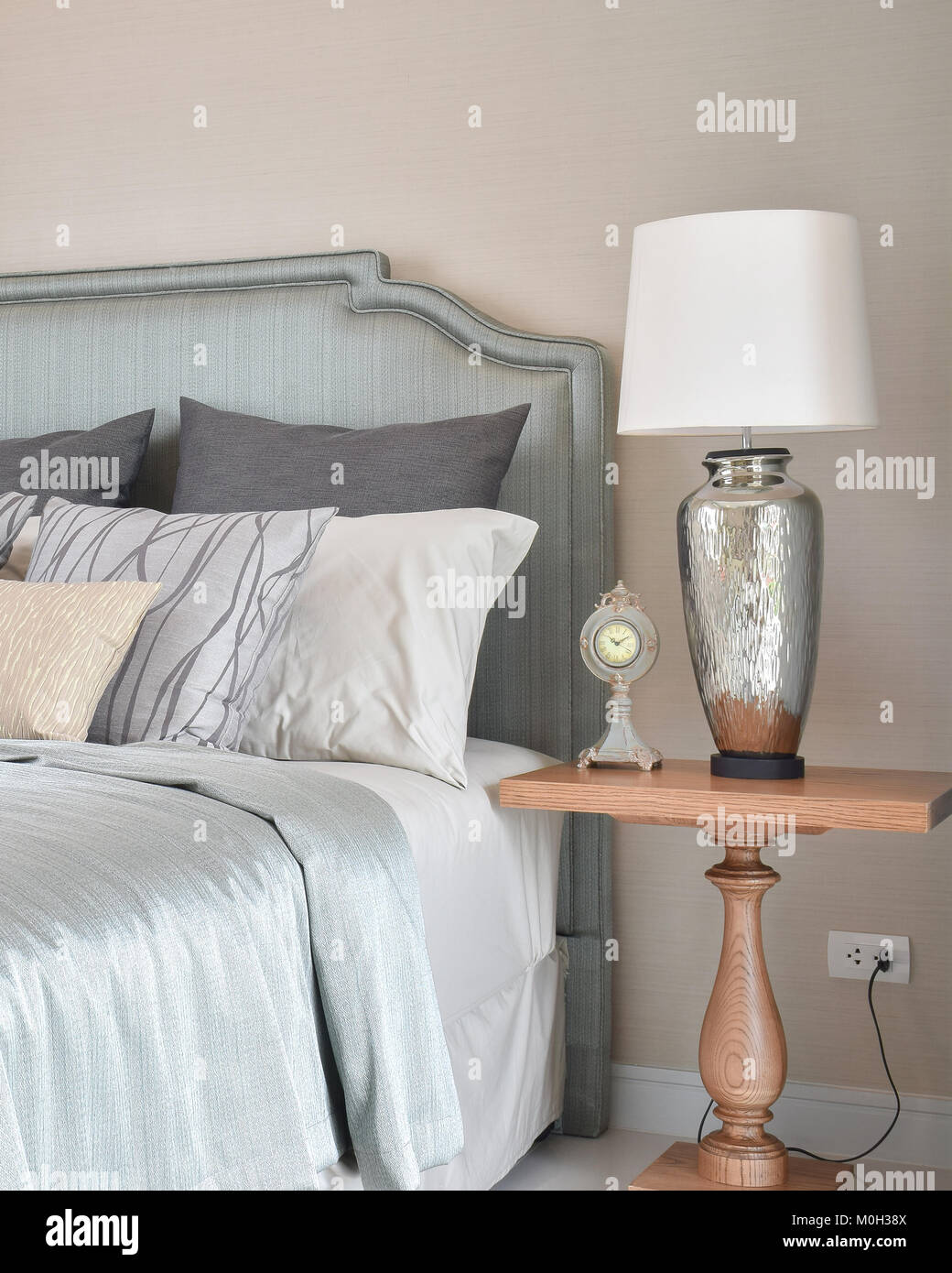 luxury bedroom interior with decorative table lamp and alarm clock on