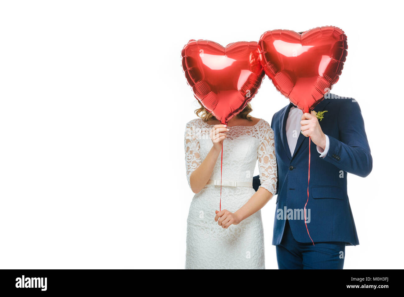 wedding couple covering faces with red heart shaped balloons isolated ...