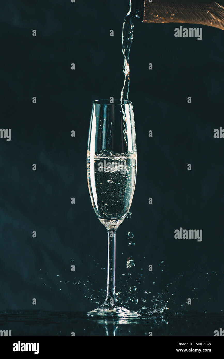 Pouring Champagne From Bottle Into Glass On Black Stock Photo - Alamy