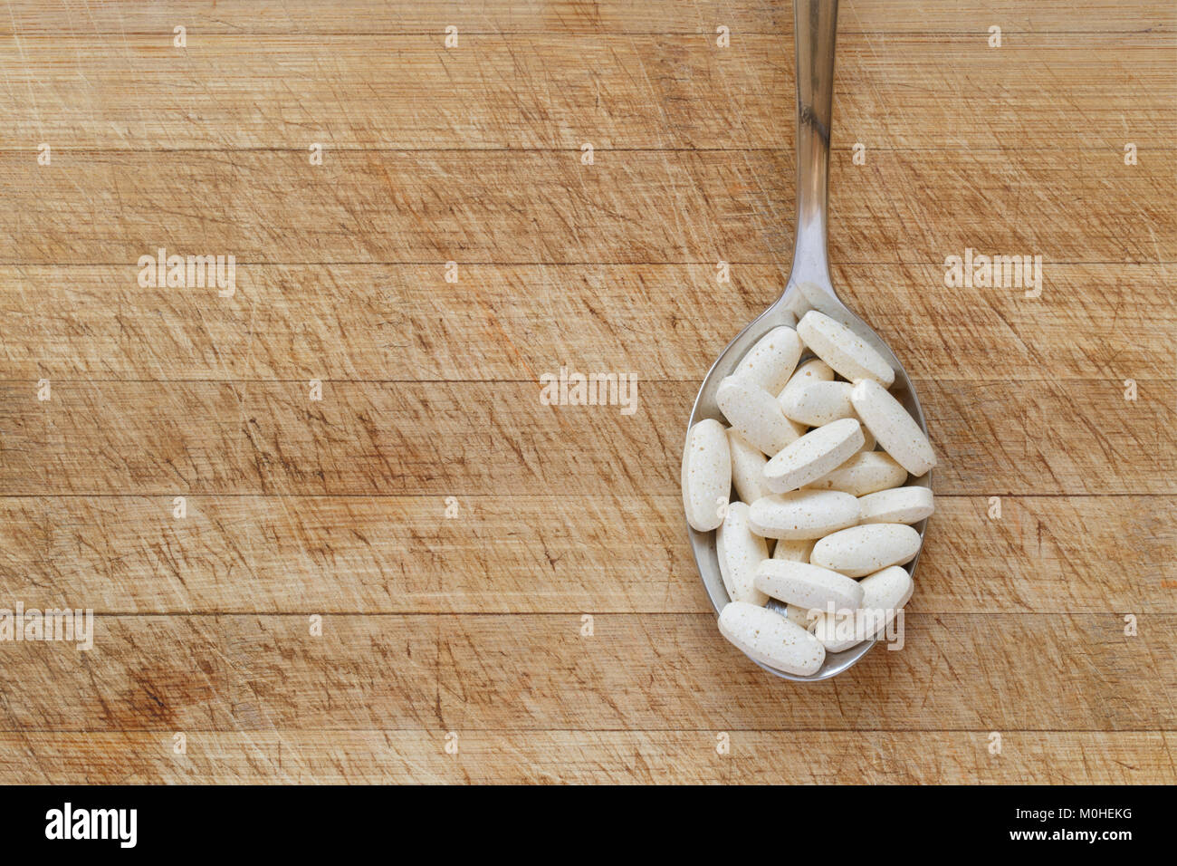 Supplement pills on spoon against cutting board background Stock Photo