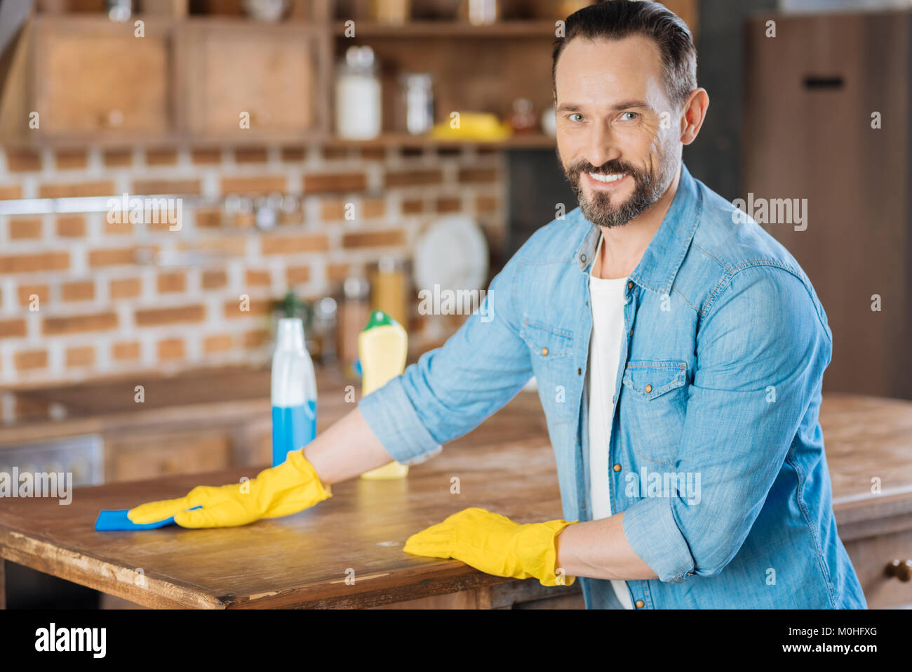 Joyful male cleaner removing dust Stock Photo