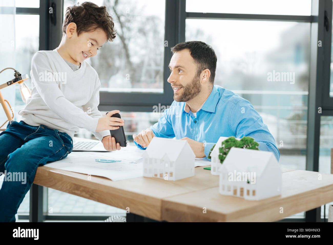 Lively boy showing funny videos to his father at work Stock Photo