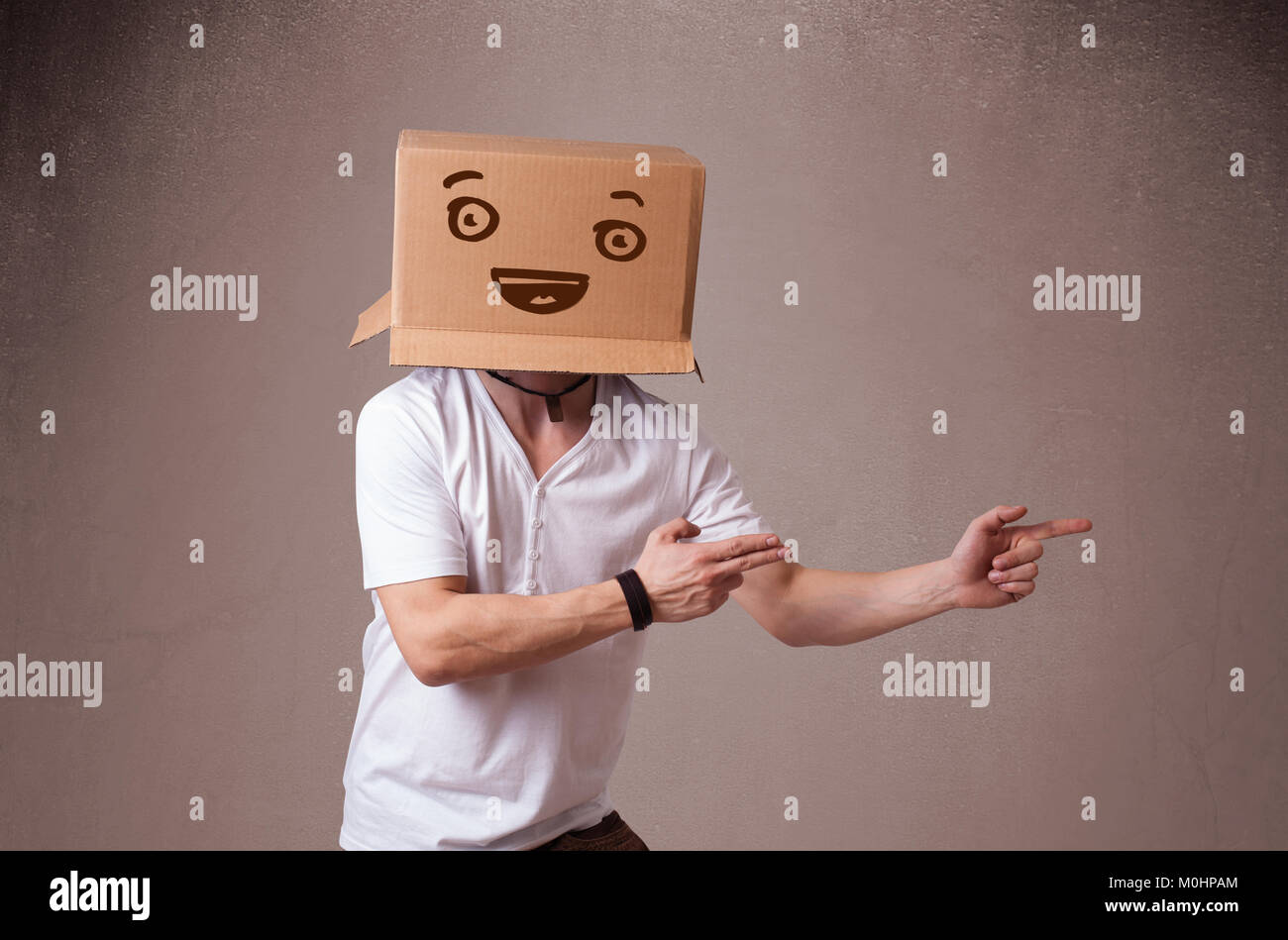 Young man standing and gesturing with a cardboard box on his head with ...