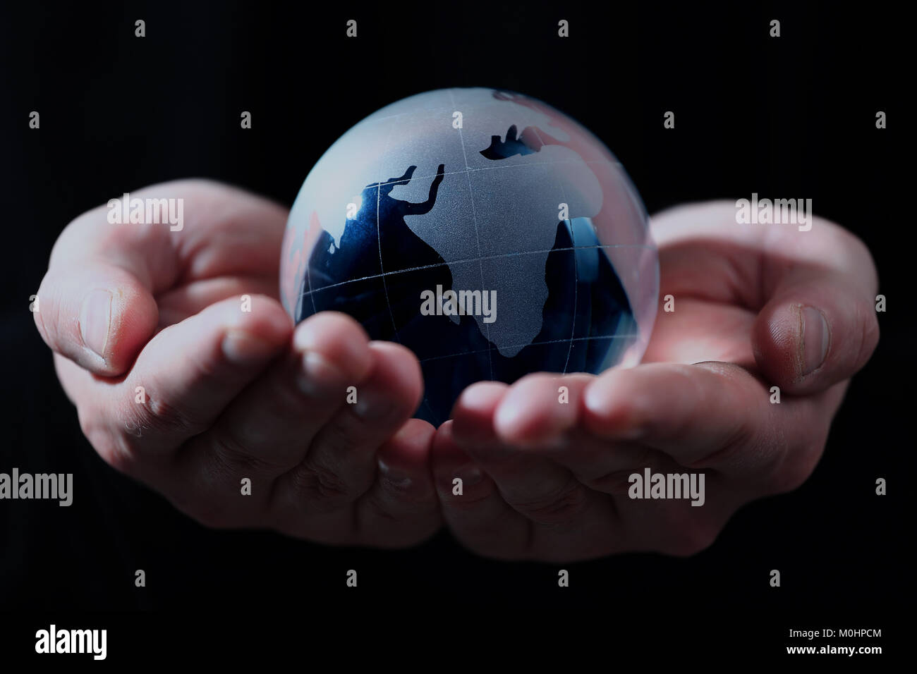 Hand holding translucent globe with blue background. Stock Photo