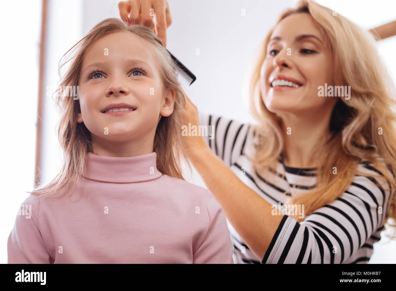 Loving mother combing her daughters hair Stock Photo