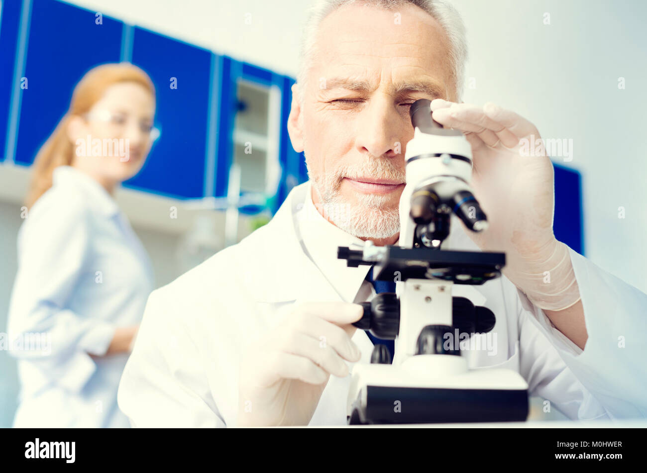 Positive Researcher Positive minded researcher looking at sample under microscope Stock ...
