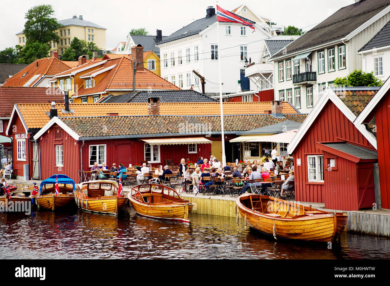 Tourists are sitting and enjoying themselves in an outdoor waterside cafe in fishing town Kragero, Norway. Stock Photo