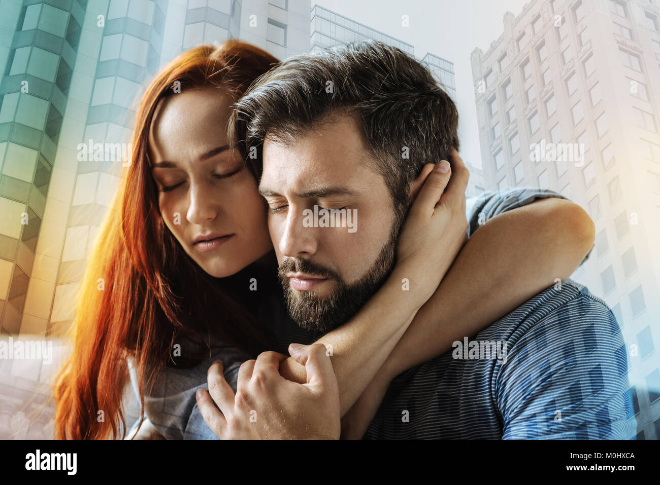 Loving woman gently hugging her boyfriend and closing her eyes Stock Photo