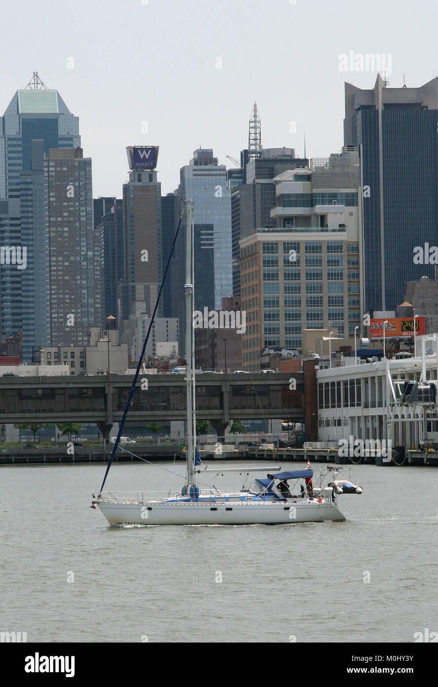 Three men on a small yacht in front of buildings on the Hudson River, Midtown West Manhattan, New York City, New York State, USA. Stock Photo