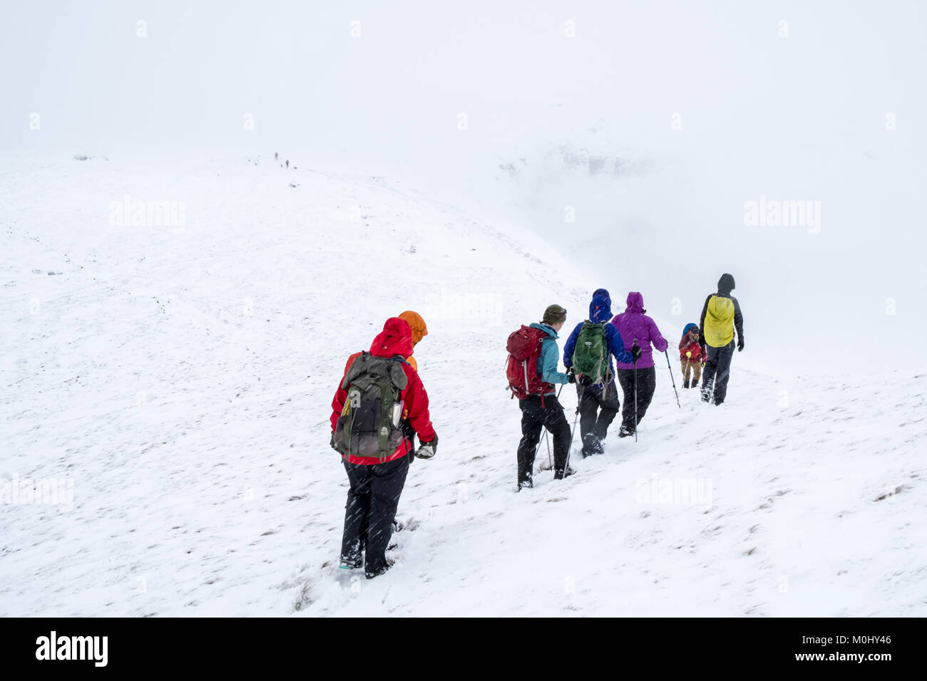 Hiking group in Winter. Walkers walking through snow on Kinder Scout