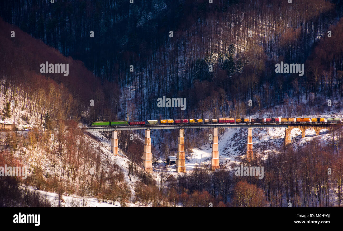 train over viaduct in winter mountains. lovely transportation scenery with snowy forested hills Stock Photo