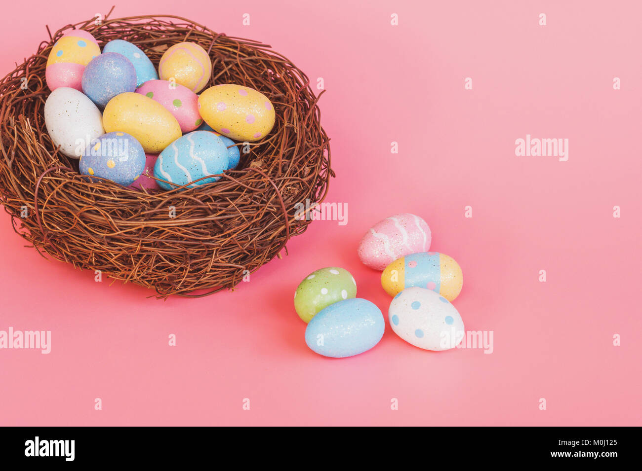 Colorful easter eggs in nest on pink pastel color background with space ...