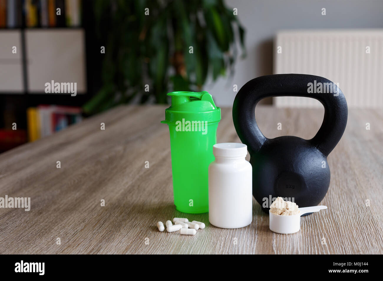 shaker bottle, kettlebell with sport supplements on wooden living room table Stock Photo
