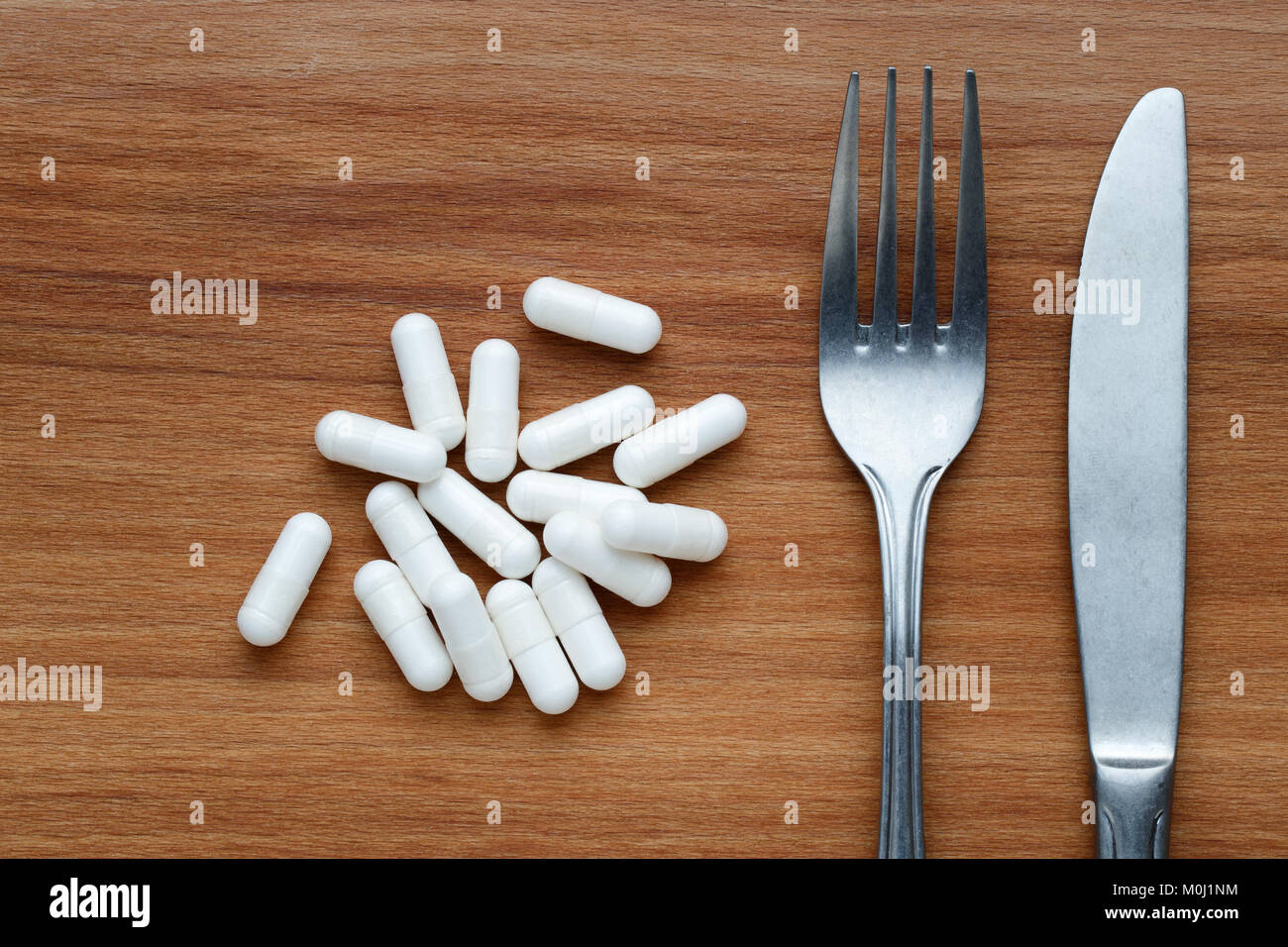 Diet concept with supplement pills, knife and fork Stock Photo