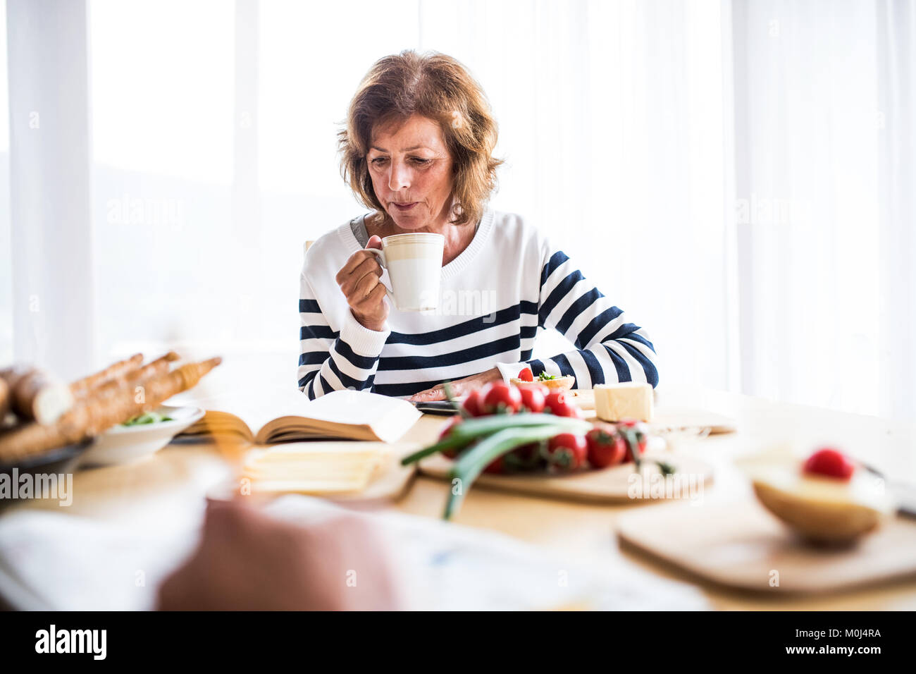 Senior woman eating breakfast at home. Stock Photo