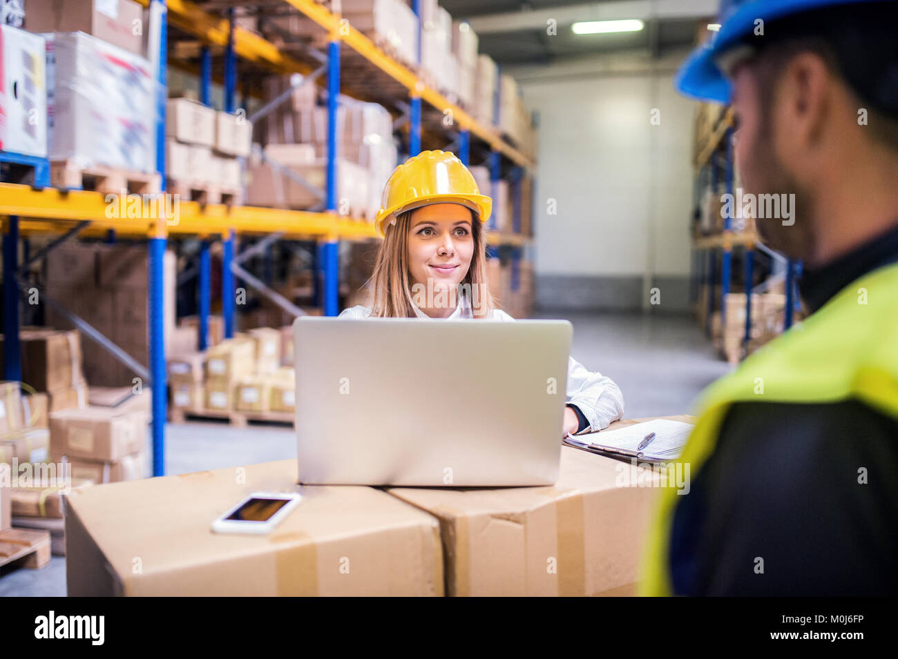 Young warehouse workers with laptop working together Stock Photo - Alamy