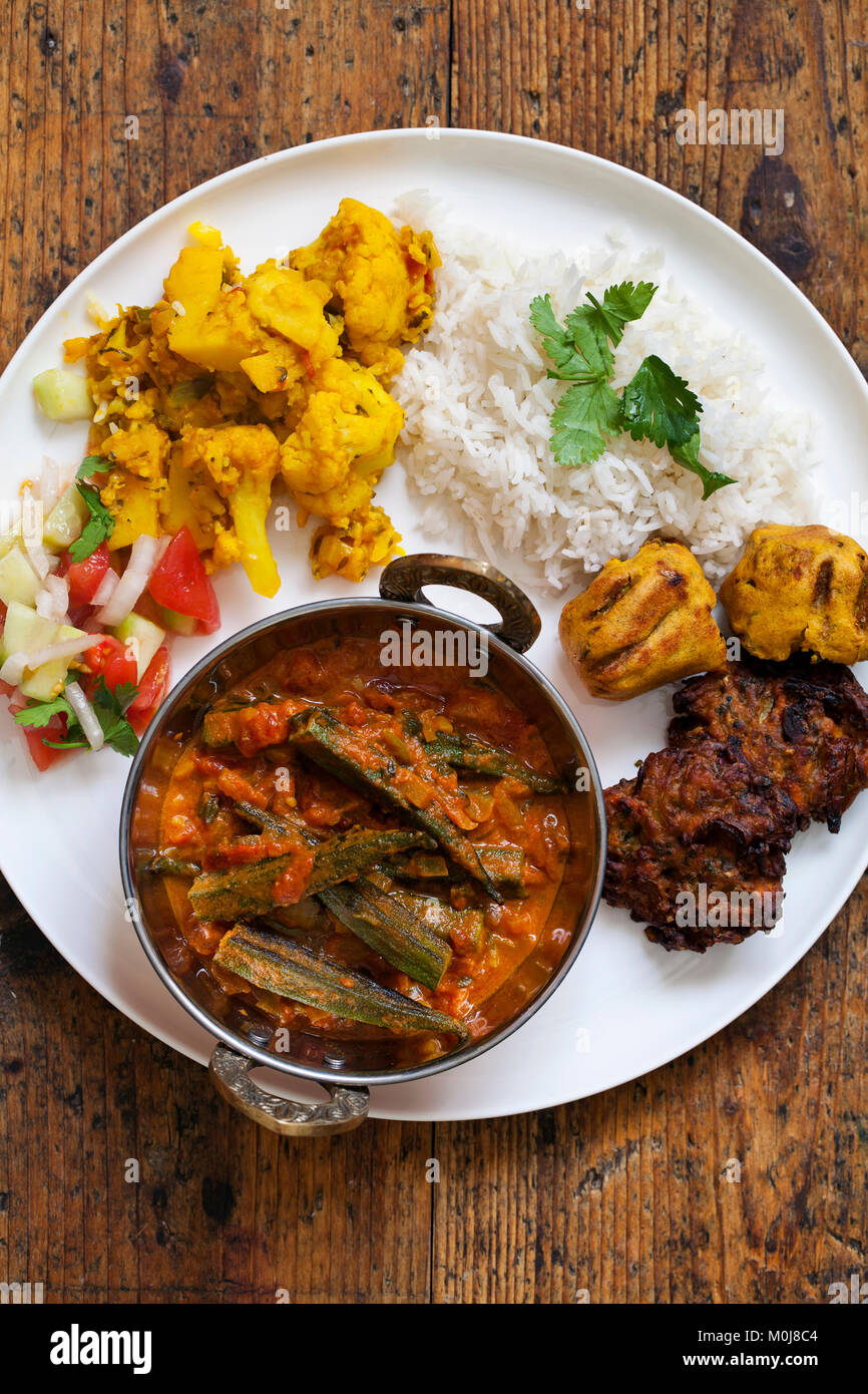 Indian meal with aloo gobi, okra curry, rice and pakoras Stock Photo