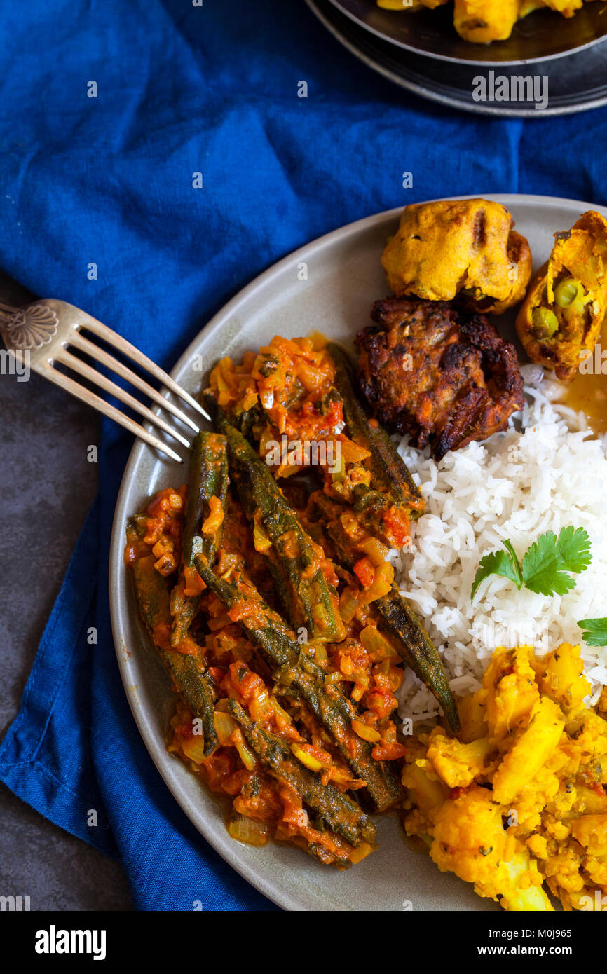 Indian meal with aloo gobi, okra curry, rice and pakoras Stock Photo