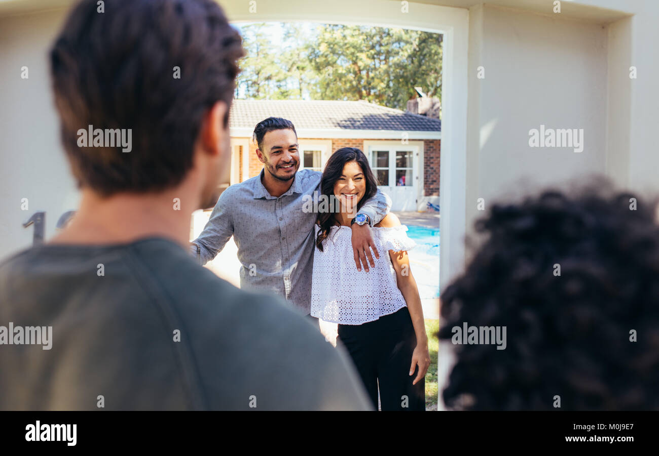 Couple inviting friend at there new house. People attending friend's housewarming party. Stock Photo